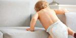 Bébé avec des couches qui monte sur le canapé